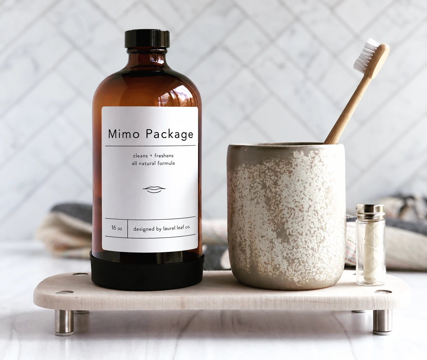 Amber glass Boston round bottle with a black screw cap beside a ceramic cup and wooden toothbrush