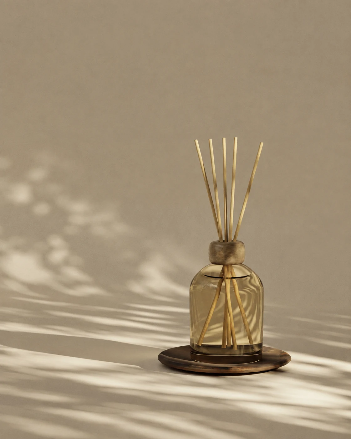 Glass reed diffuser on a dark round tray in warm sunlight